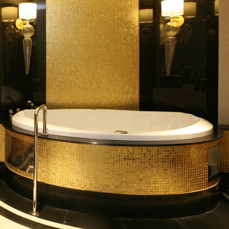 A bathtub in a bathroom with gold tiles