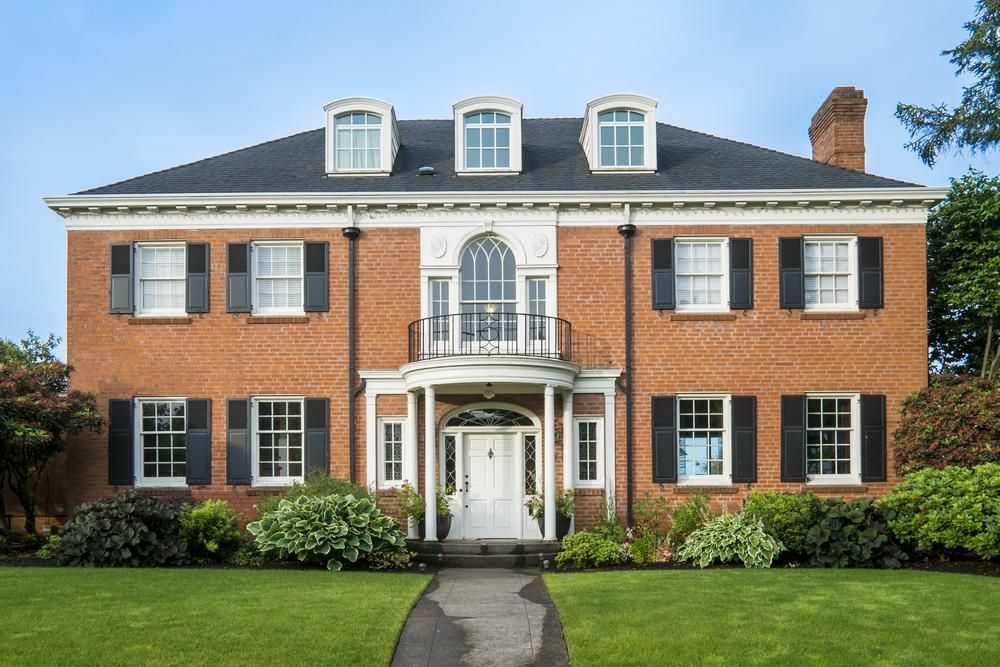 A large brick house with black shutters and a white door