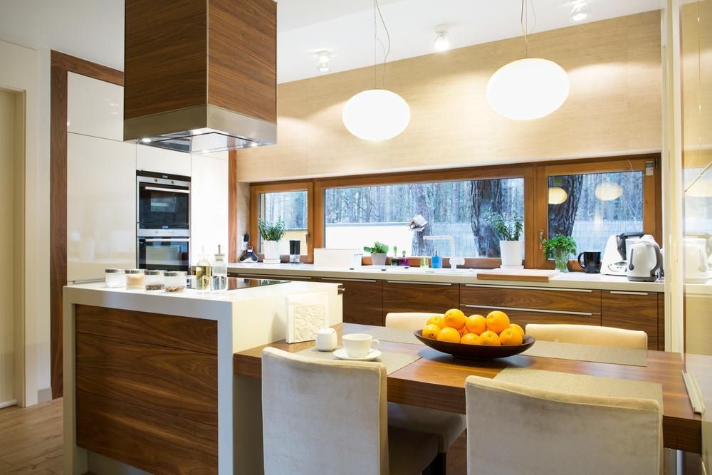 Cozy contemporary kitchen remodel design with natural wood base cabinets and natural stone waterfall island.