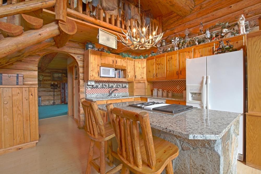 Country log cabin rustic farm style kitchen remodel design with solid natural stone base and countertop island.