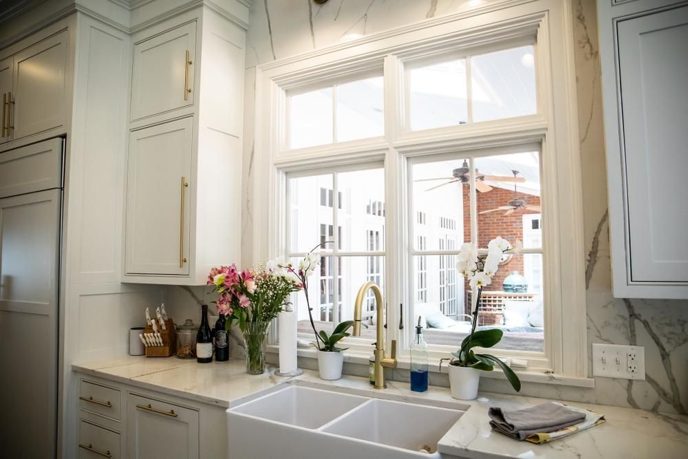 Cream colored farmhouse style kitchen with double-basin porcelain sink and painted solid wood cabinets.