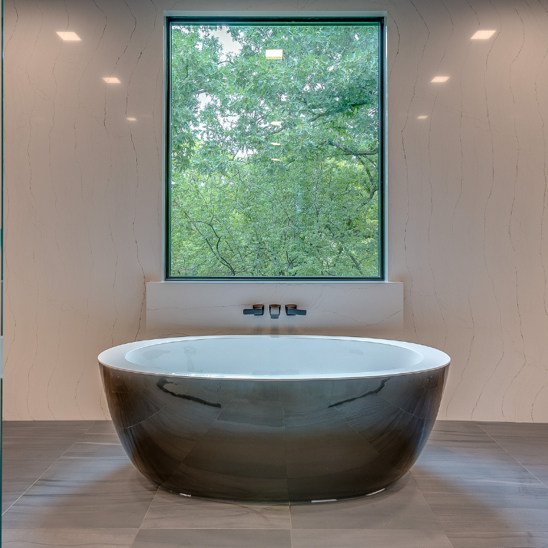 A bathtub in a bathroom next to a window with trees in the background.