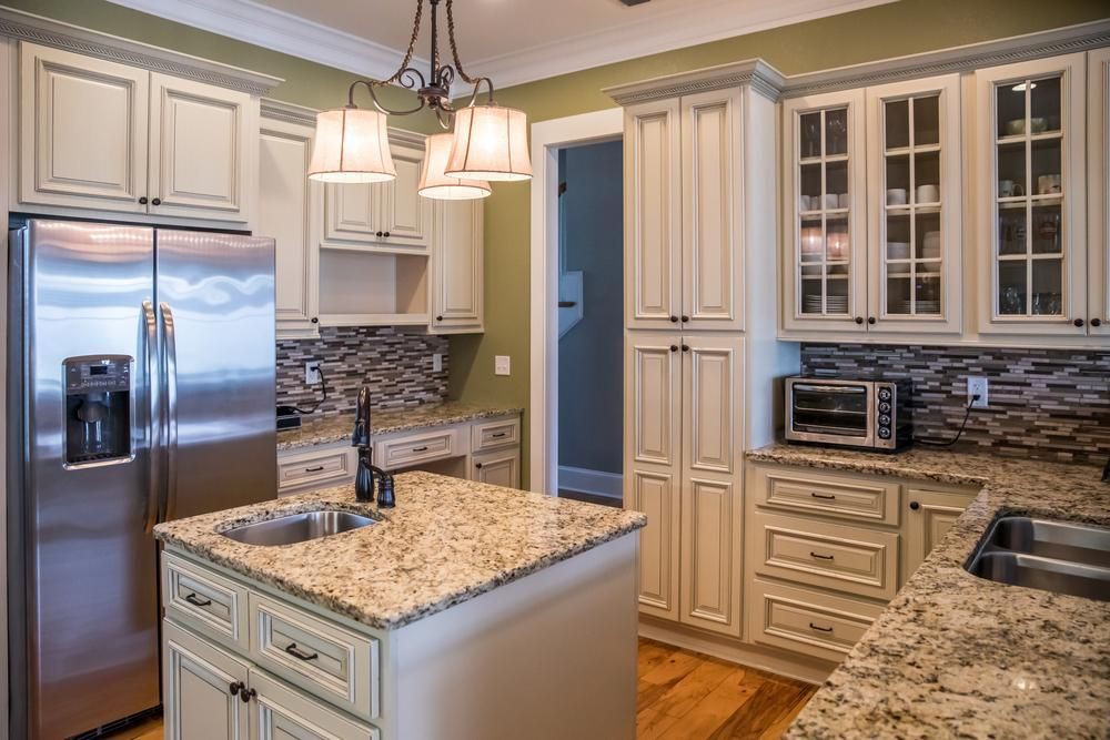 Cream colored french farmhouse style kitchen remodel with granite stone countertops and painted solid wood cabinets.