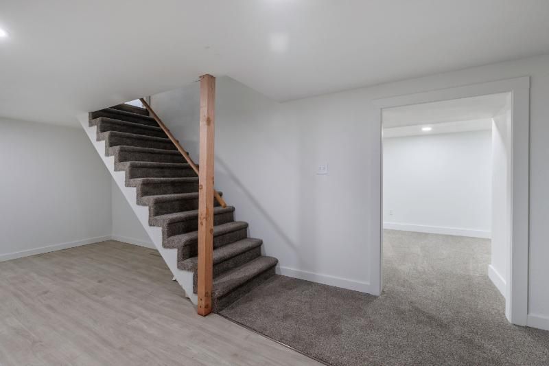 An empty basement with stairs leading up to the second floor.