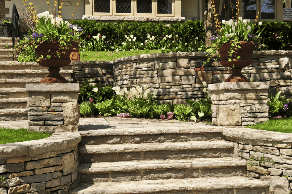 A stone staircase leading up to a house with flowers in pots.