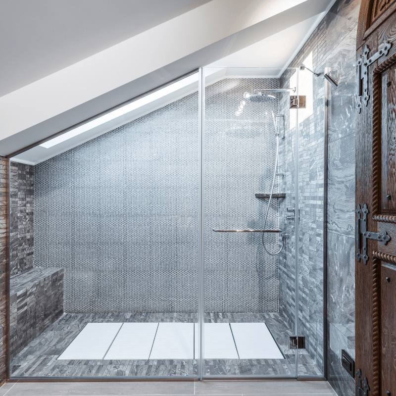 A bathroom with a walk in shower with a glass door.