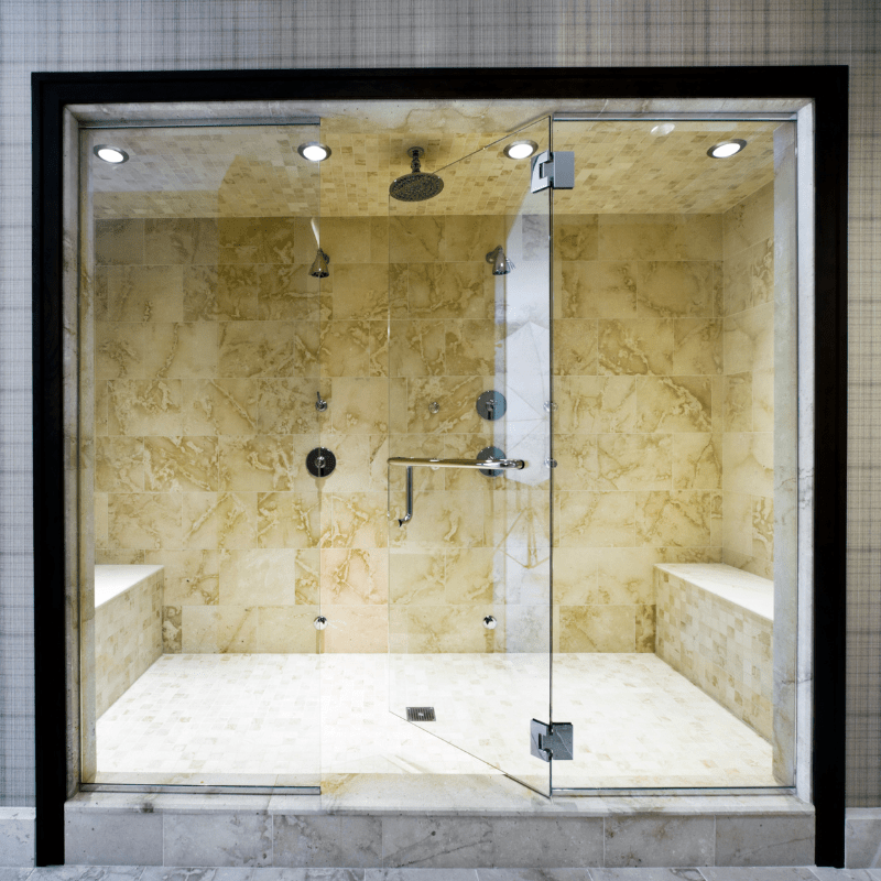 A bathroom with a walk in shower with a glass door