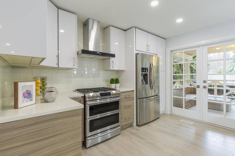 Modern farm style kitchen with white laminate cabinets, natural stone countertops and stainless steel appliances.