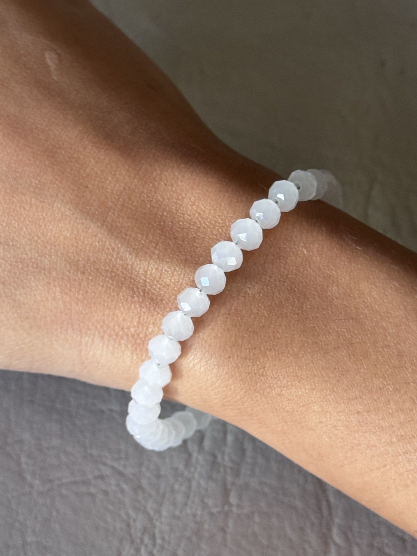 Una persona que lleva una pulsera con cuentas blancas en la muñeca