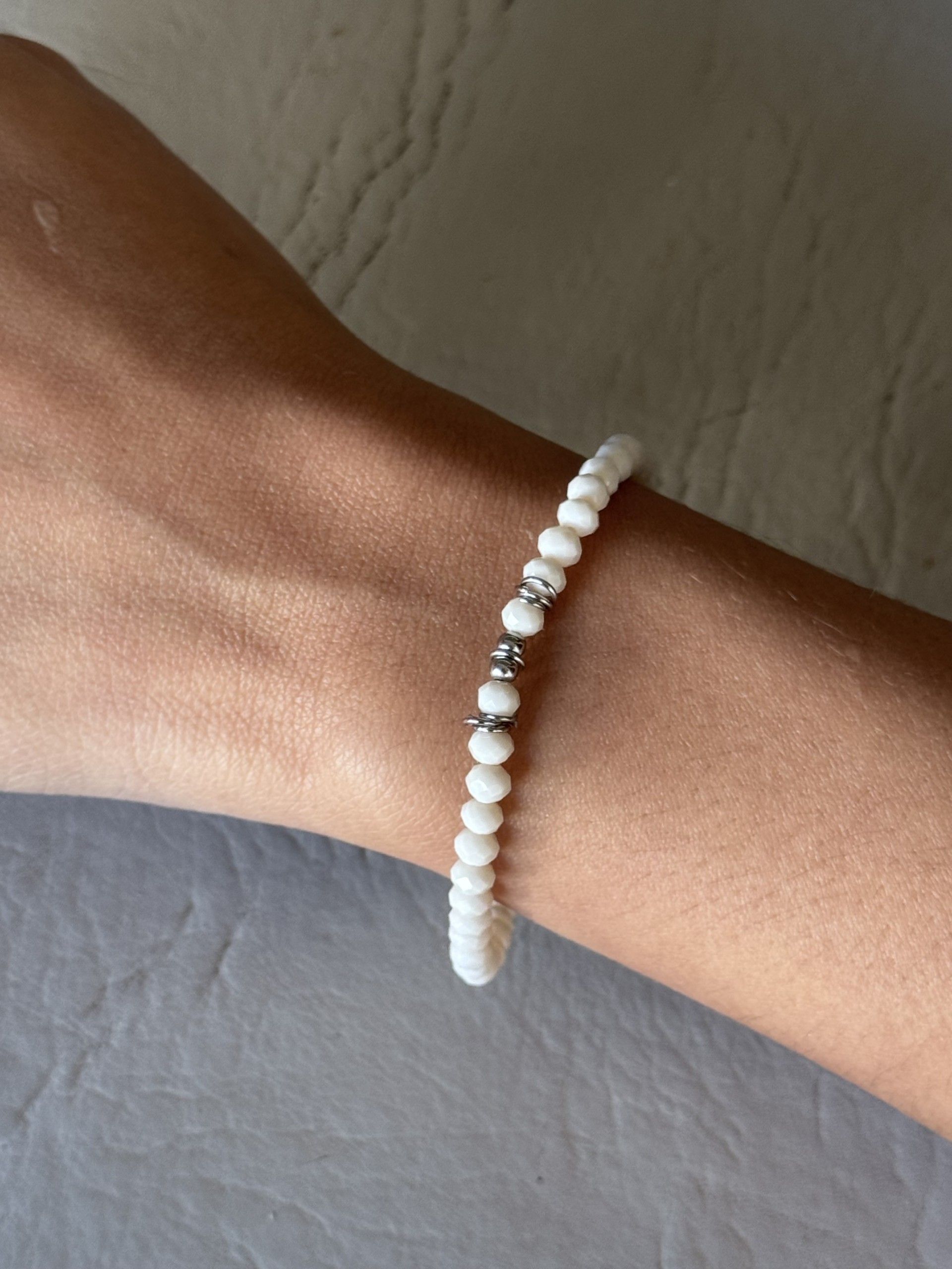 Una persona que lleva una pulsera con cuentas blancas en la muñeca