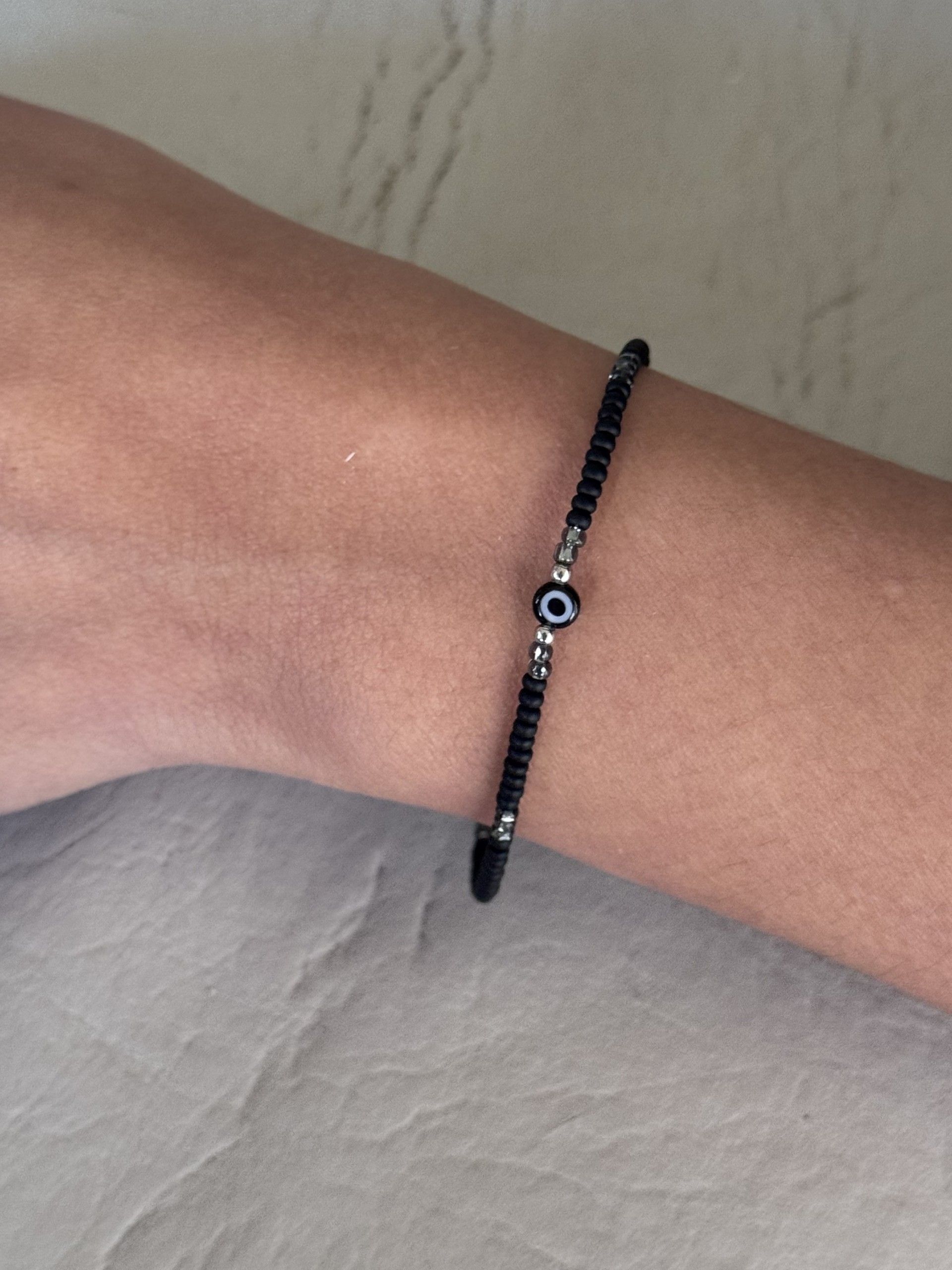 Una persona que lleva una pulsera negra con un mal de ojo.