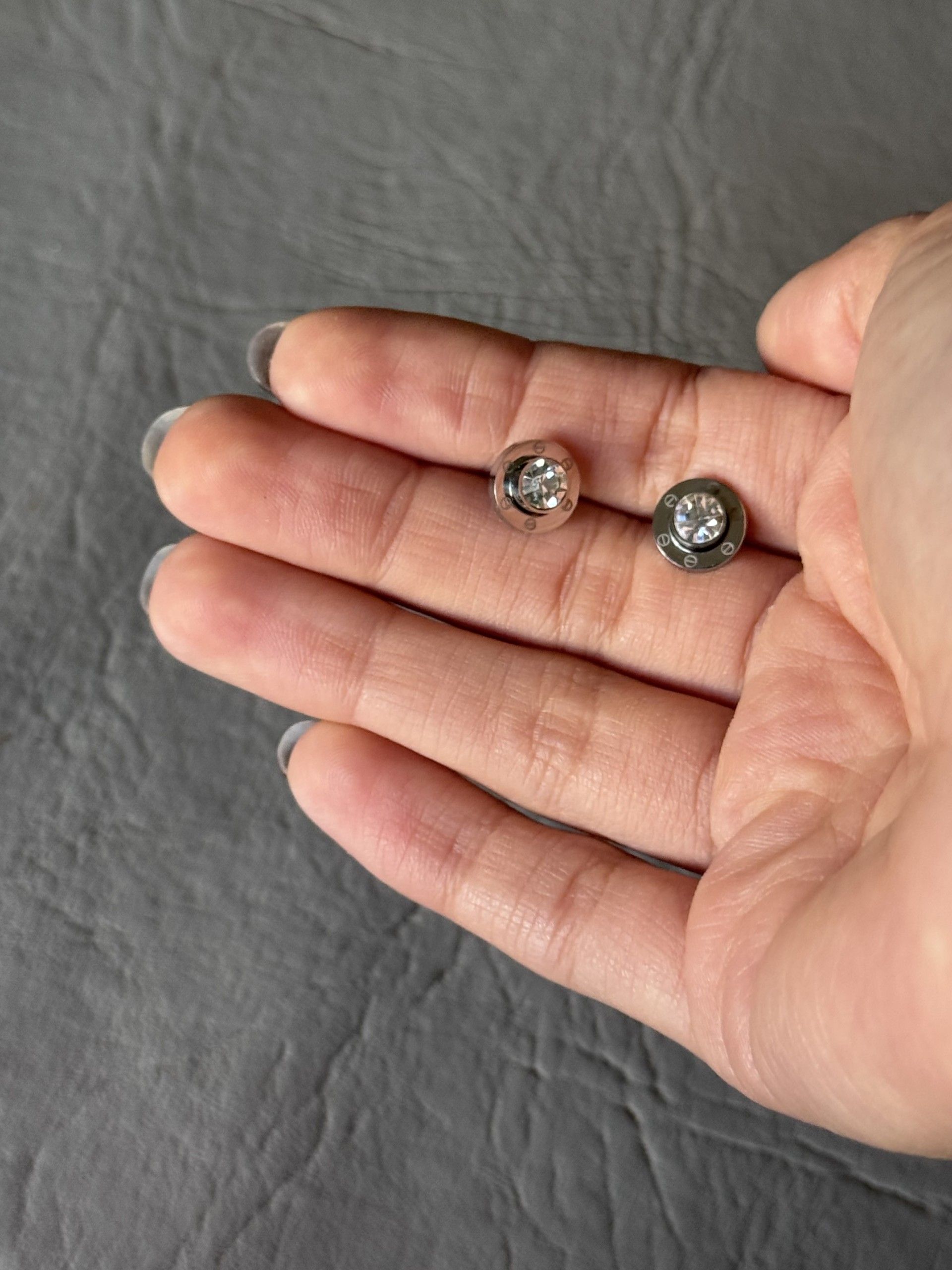 Una persona sostiene un par de pendientes en su mano.