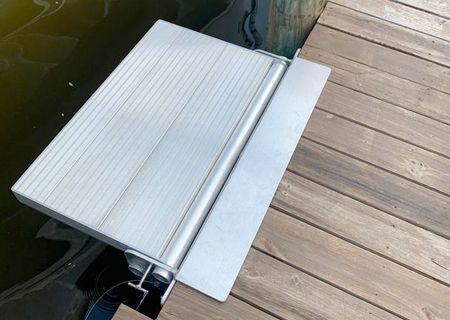 Aluminum ramp leading from a wooden dock into water.