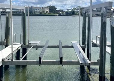 Boat lift in a waterway with buildings in the background.