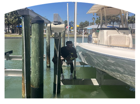 Person working on a boat lift, near a boat, dock, and water.
