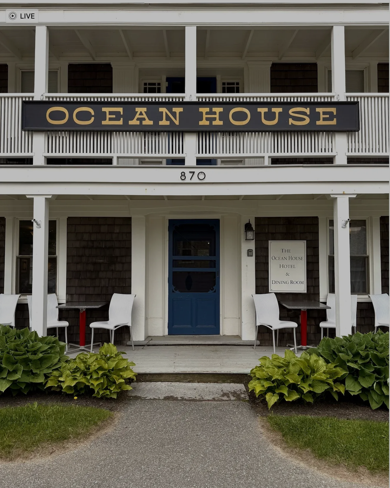 Front entrance of Ocean House with blue door, white porch, and hanging sign above the steps.