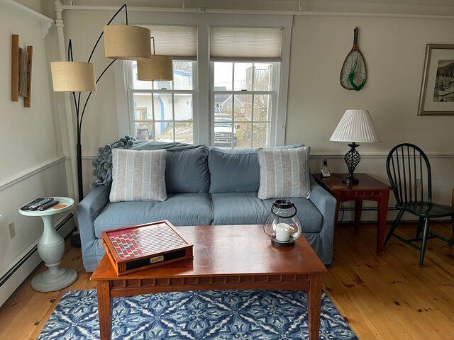 Bright bedroom with two twin beds, patterned blue bedding, and a window with white curtains.