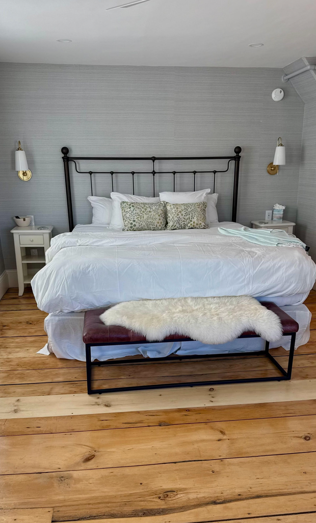 Cozy bedroom with a blue quilted bed, striped pillows, green nightstand, and framed wall art