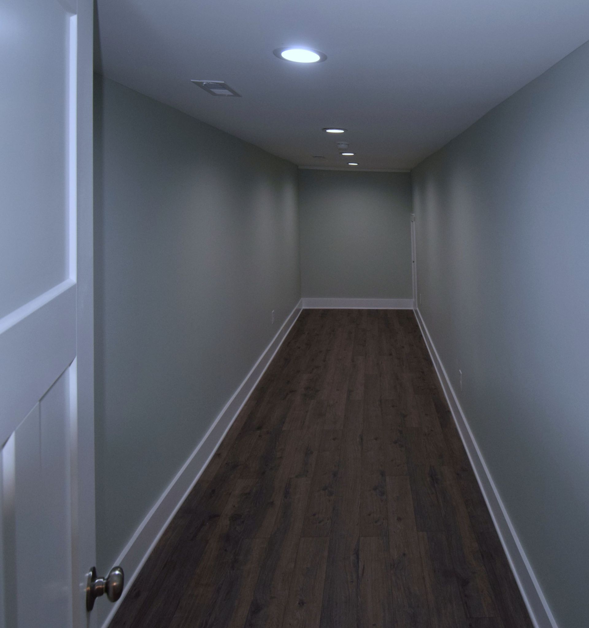 An empty hallway with wooden floors and gray walls