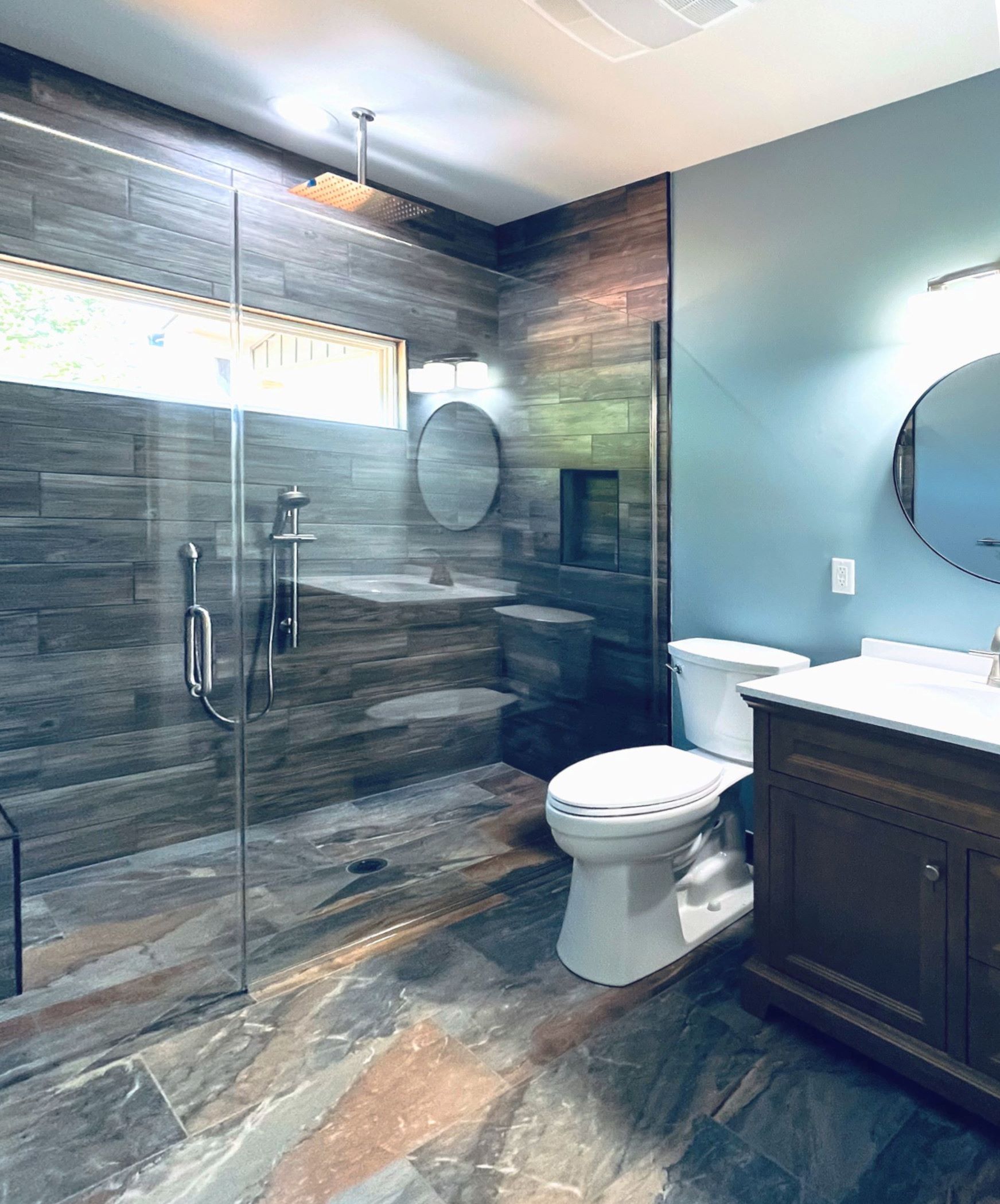 A bathroom with a toilet , sink , shower and mirror.