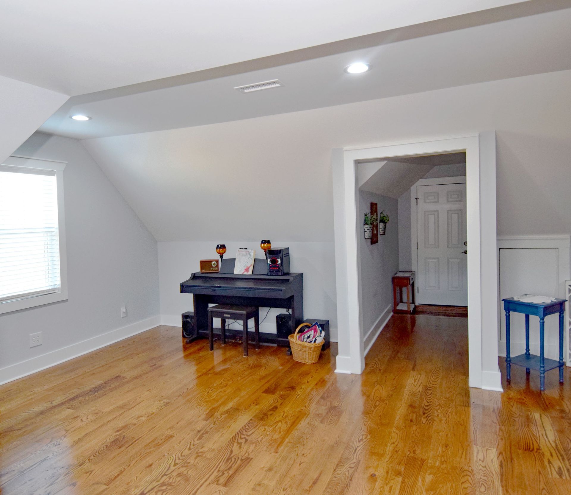 A living room with hardwood floors and a piano.