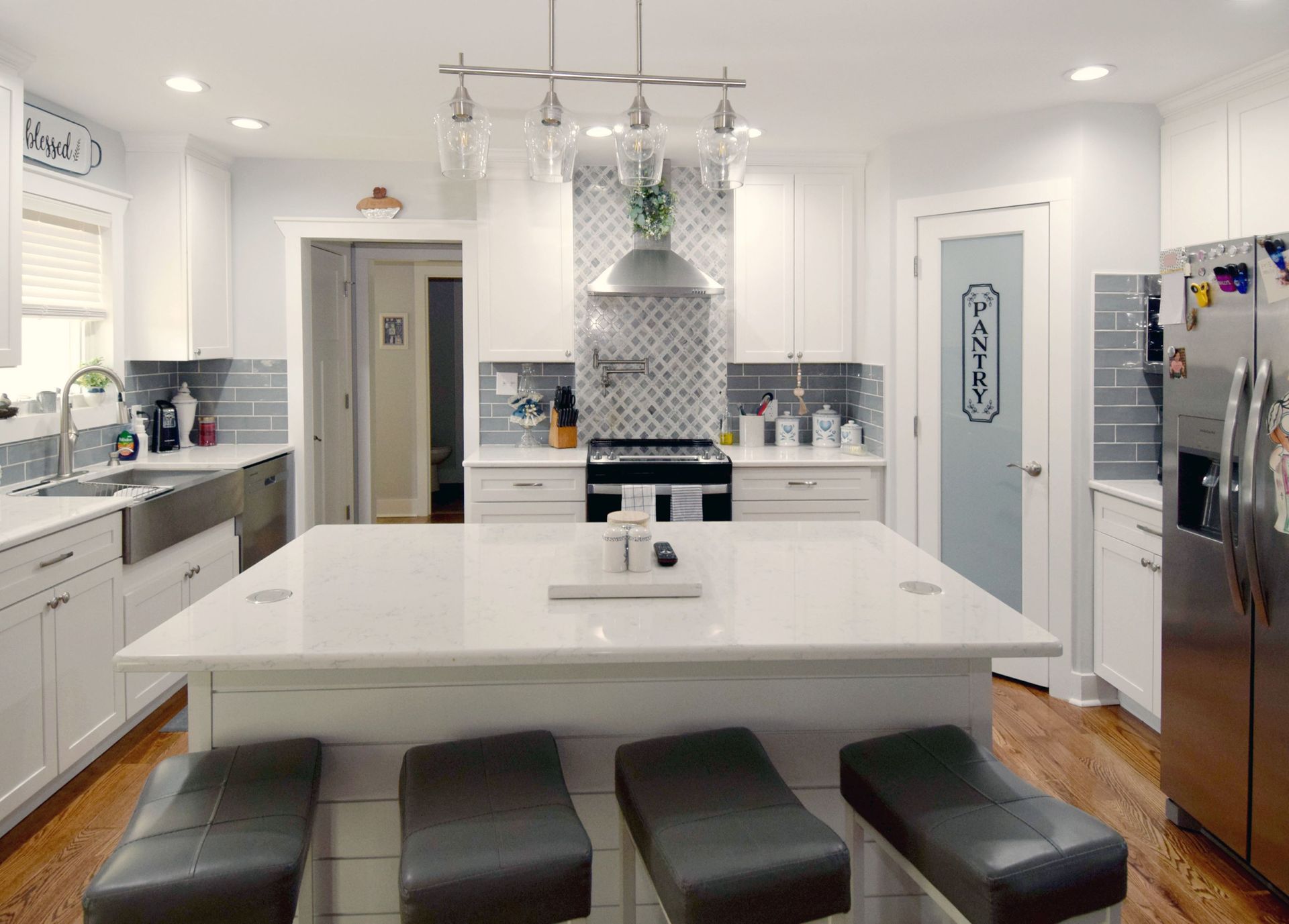 A kitchen with white cabinets , stainless steel appliances , and a large island.