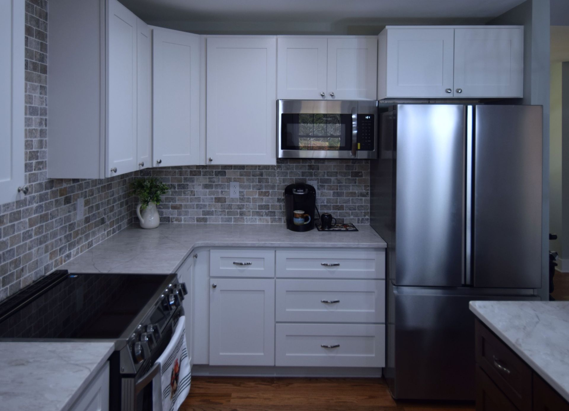 A kitchen with white cabinets , stainless steel appliances , a stove and a refrigerator.