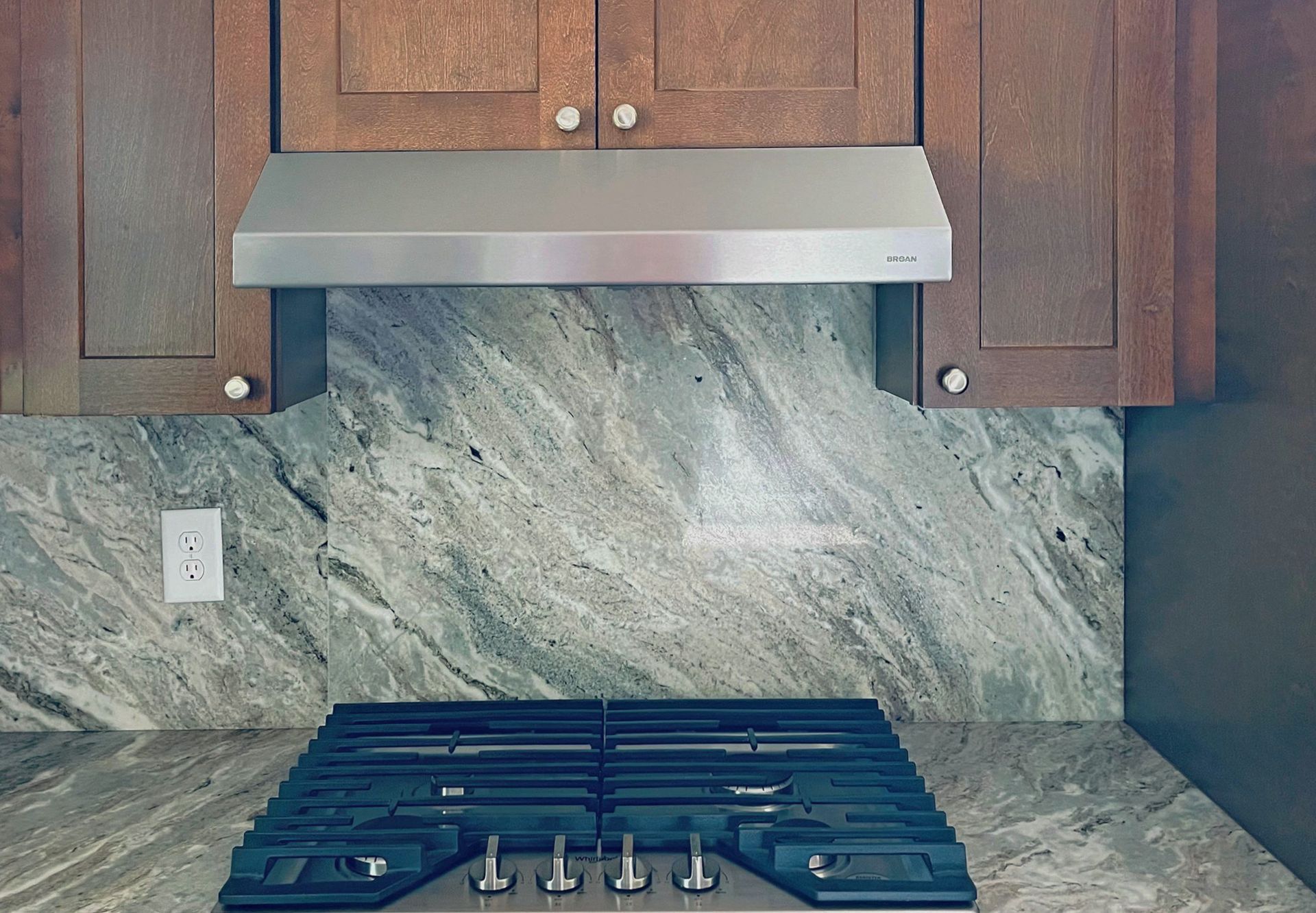 A stove top oven with a stainless steel hood above it