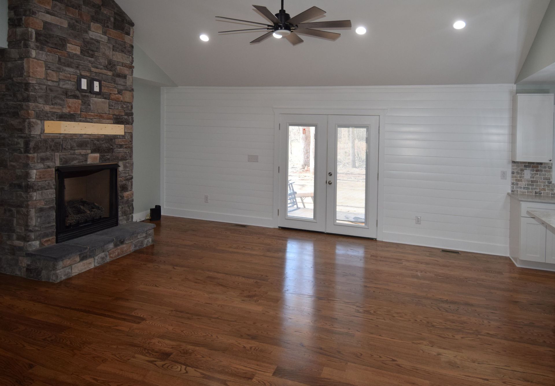 An empty living room with a fireplace and a ceiling fan.
