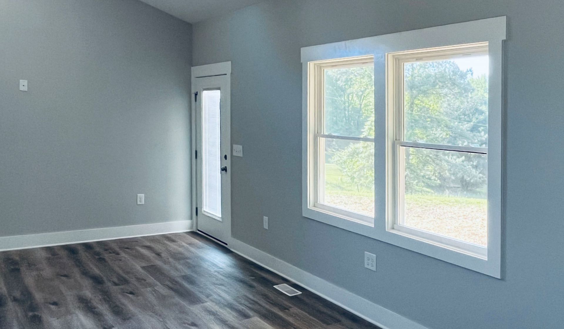An empty room with two windows and a door.