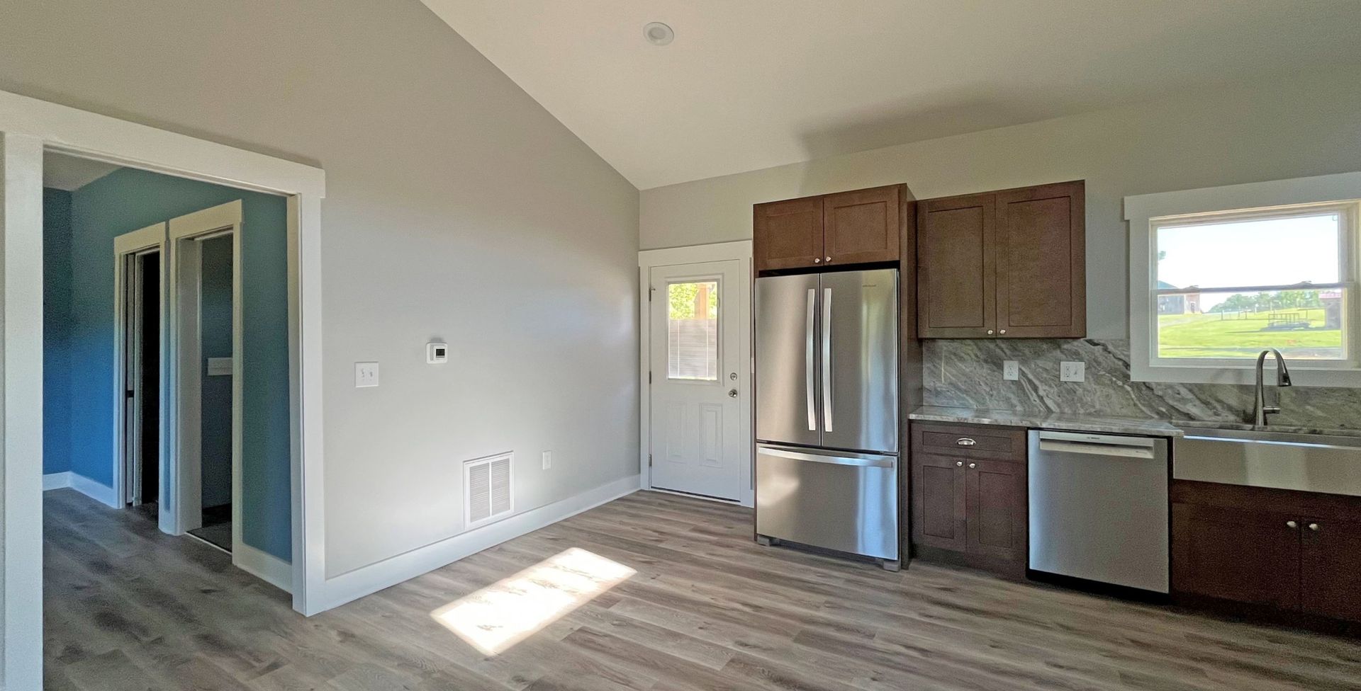 An empty kitchen with stainless steel appliances and wooden cabinets.