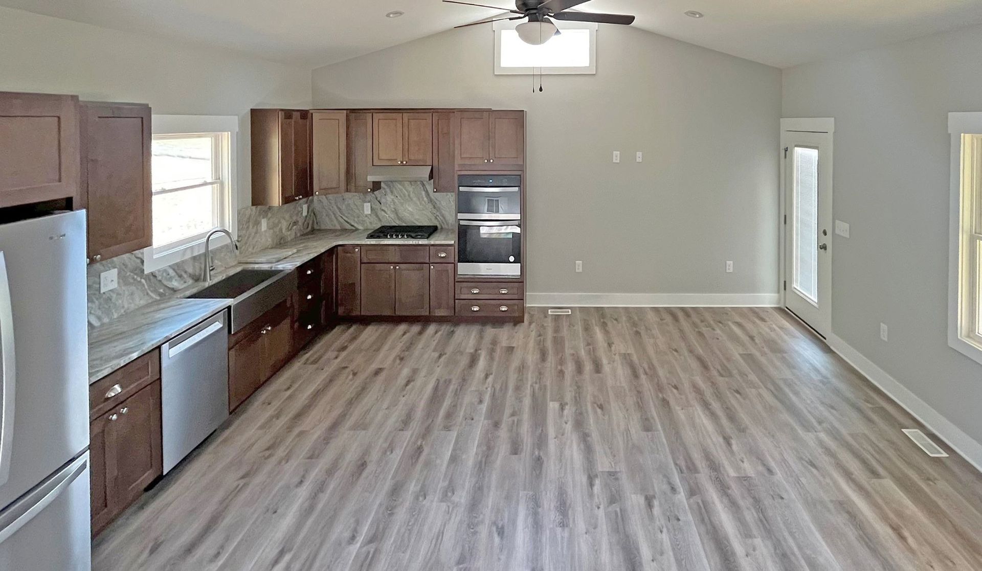 An empty kitchen with wooden floors and a ceiling fan.