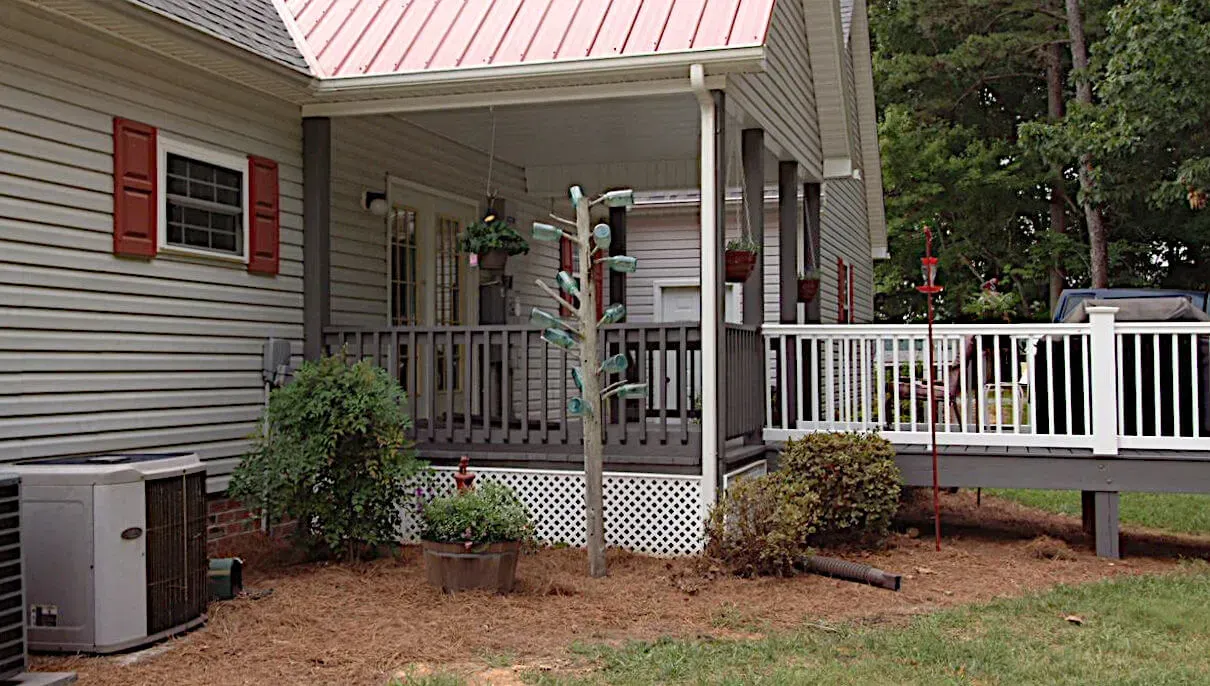 A white house with a pink roof and a porch.