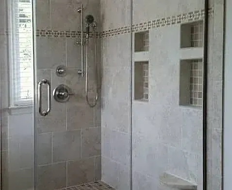 A bathroom with a walk in shower with a glass door.