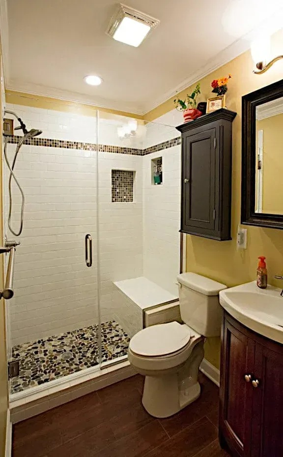 A bathroom with a toilet , sink , shower and mirror.