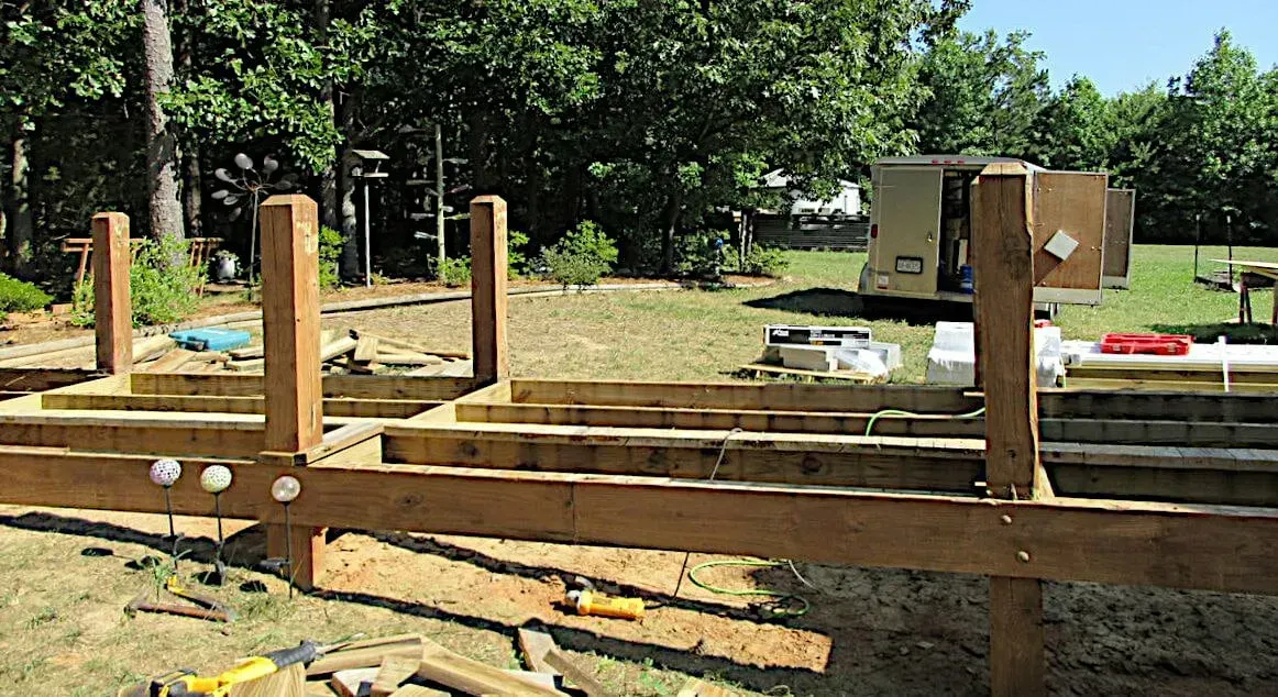 A wooden deck is being built in a backyard.
