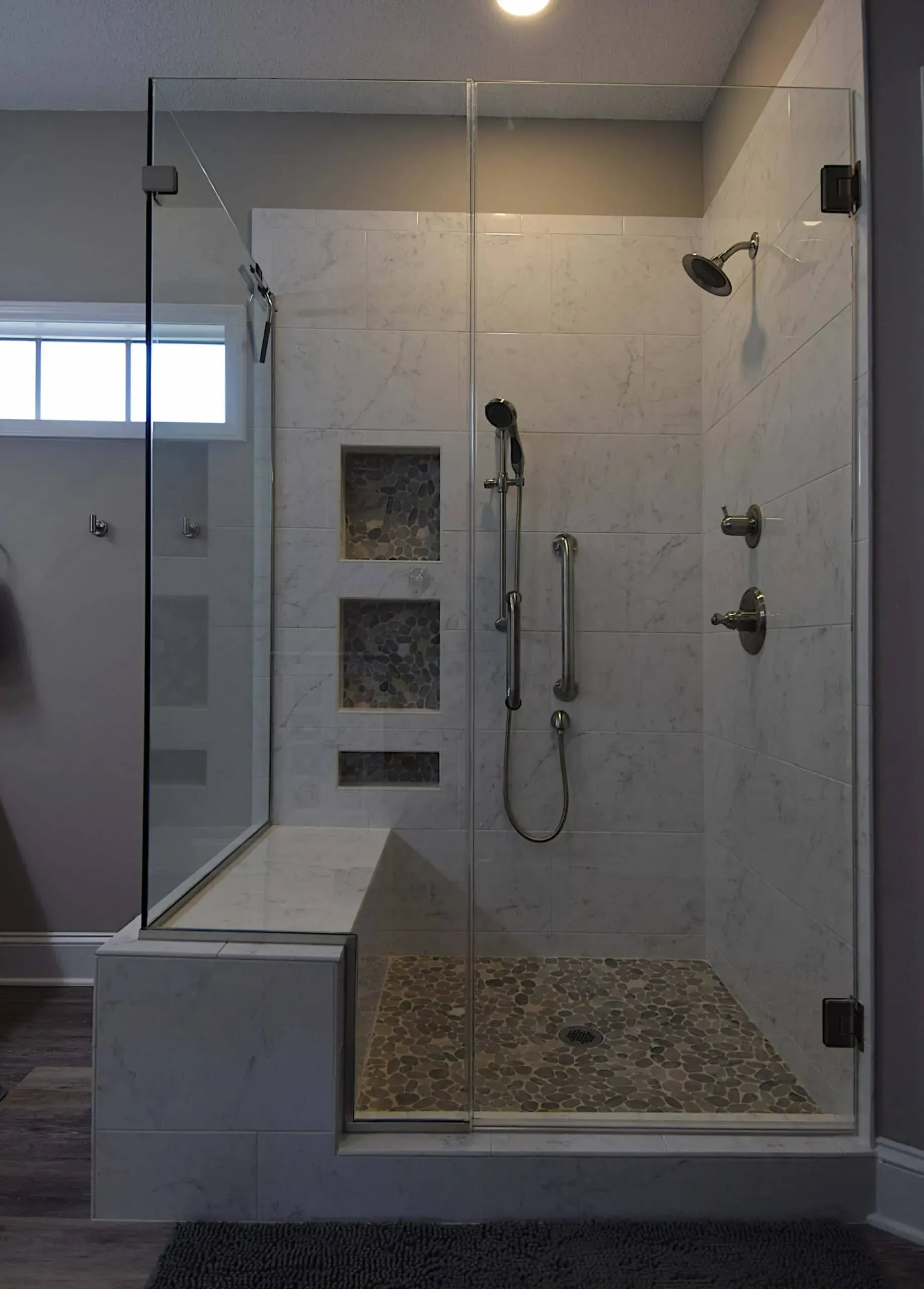 A bathroom with a walk in shower with a glass door