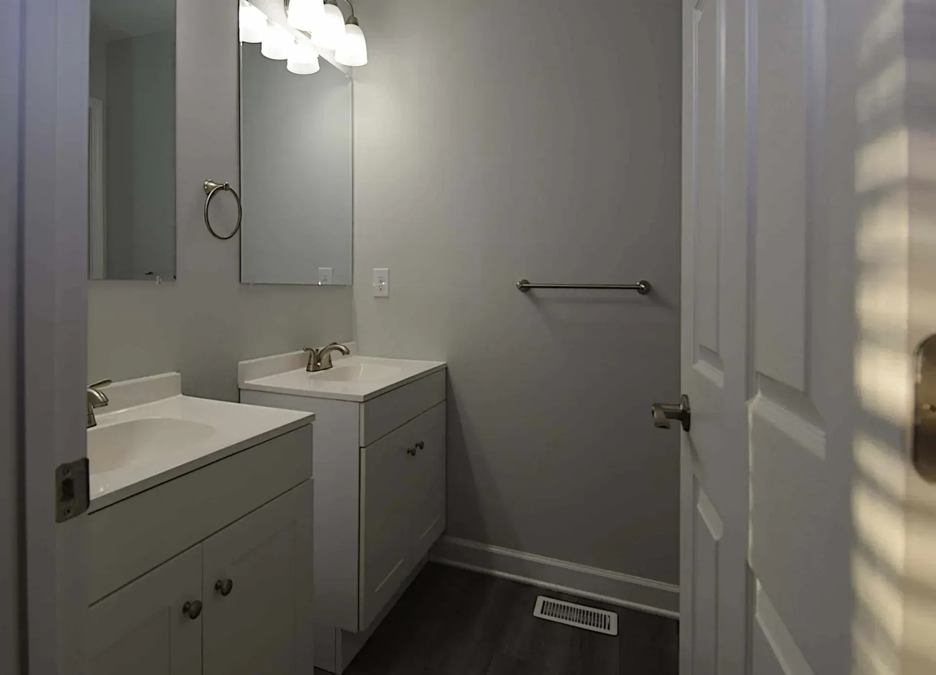 A bathroom with two sinks , a mirror and a towel rack.