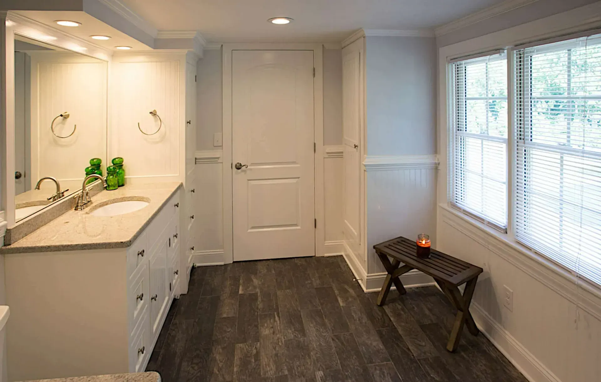 A bathroom with two sinks , a mirror and a bench.