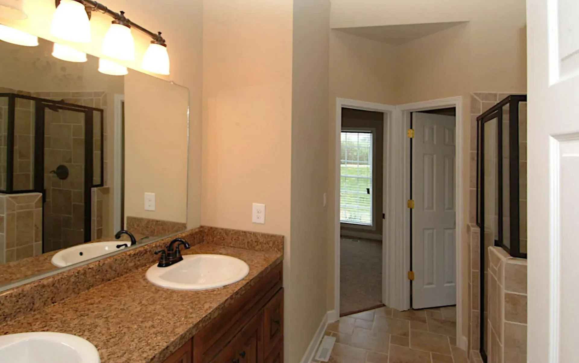 A bathroom with two sinks and a shower.