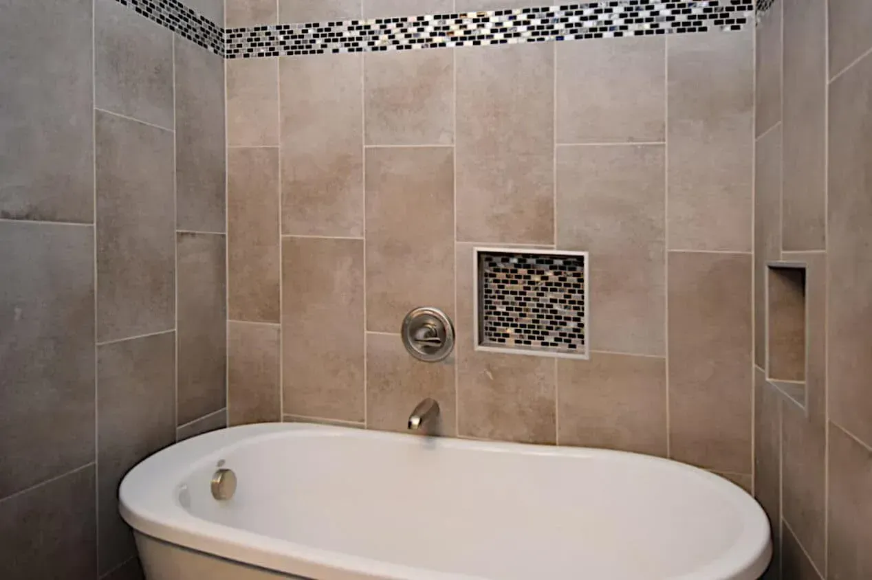 A bathtub is sitting in a bathroom next to a tiled wall.
