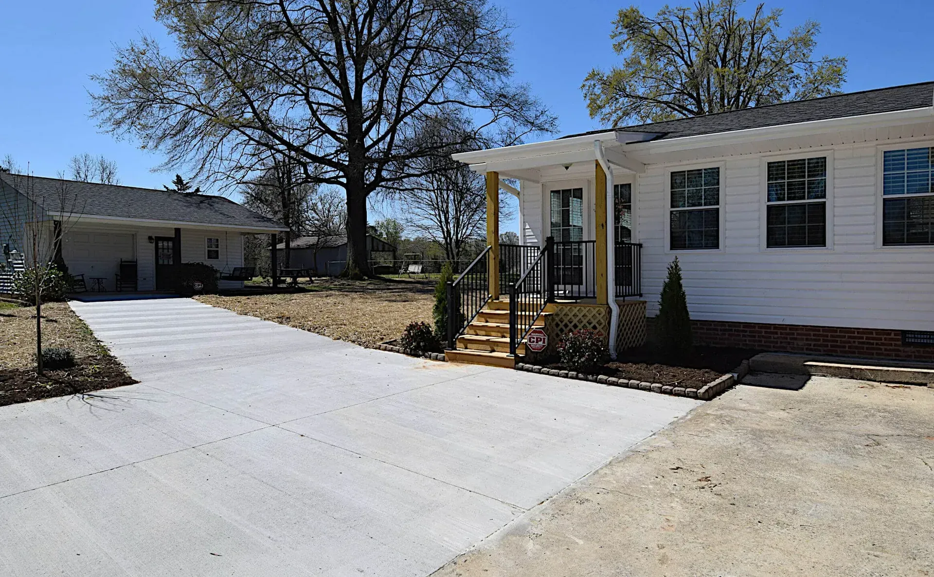 A white house with a yellow porch is next to another white house