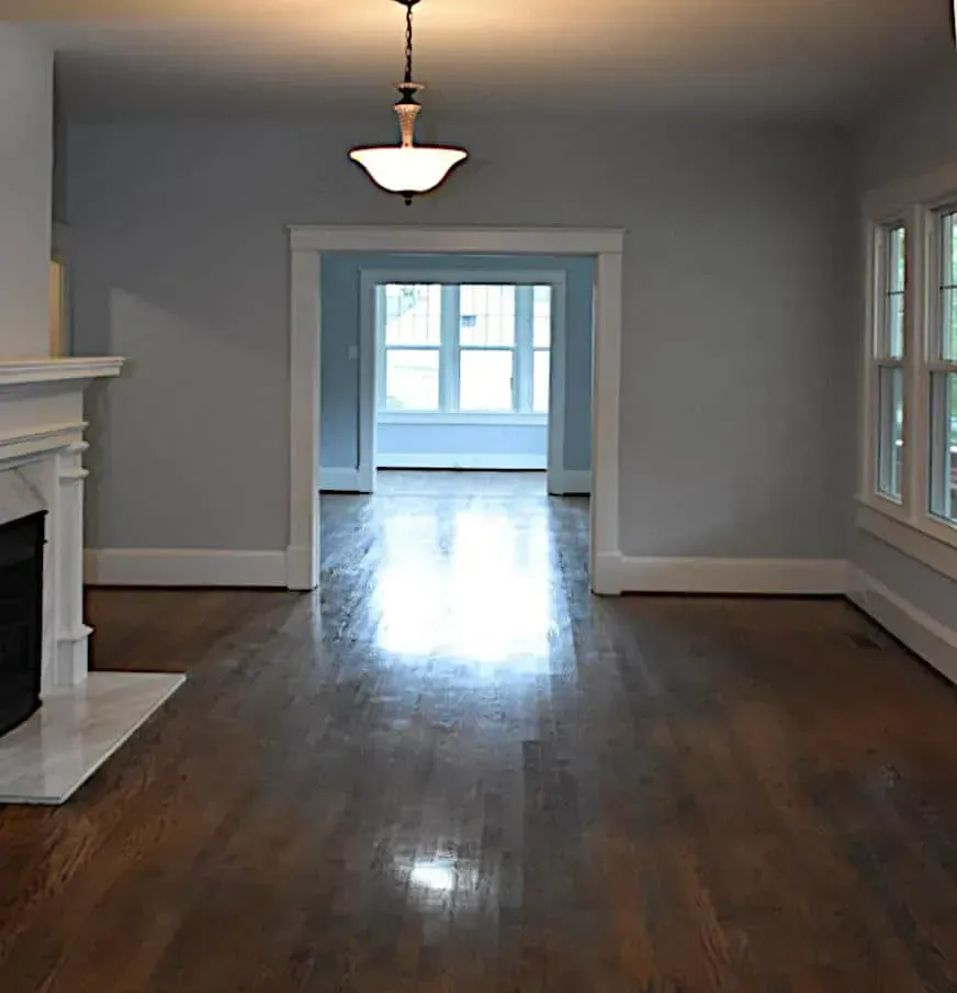 An empty living room with hardwood floors and a fireplace.