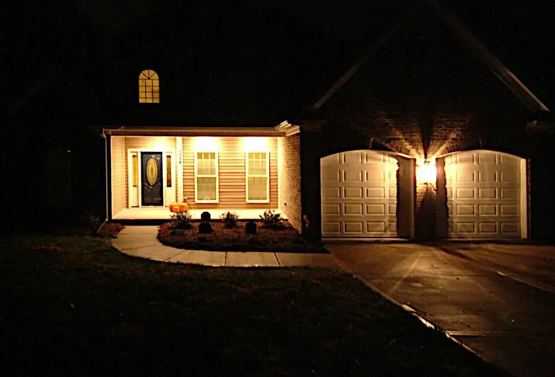 A house with two garage doors is lit up at night.