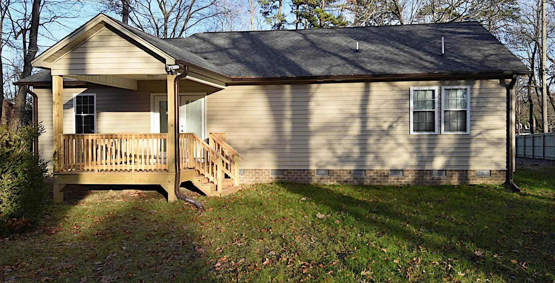 A small house with a porch and stairs is sitting on top of a lush green field.