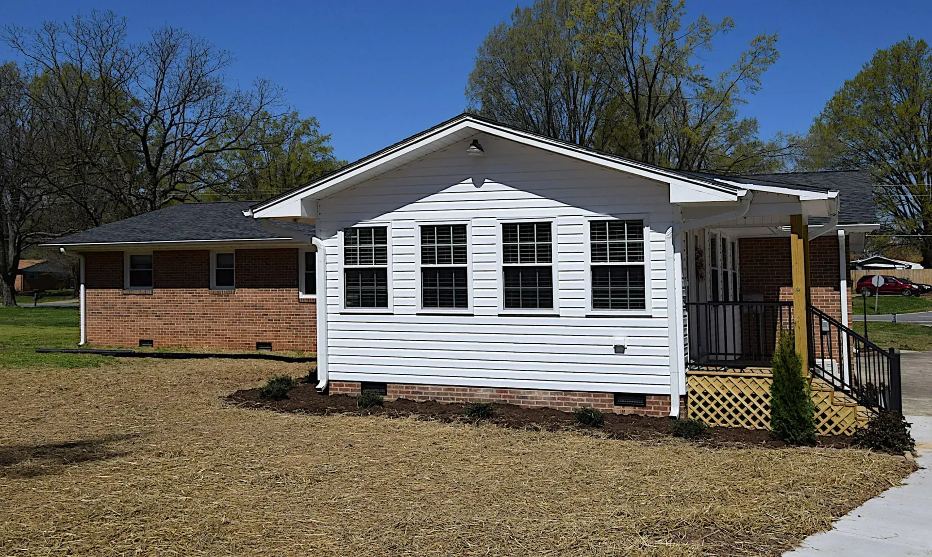 A small white house with a brick wall and shutters