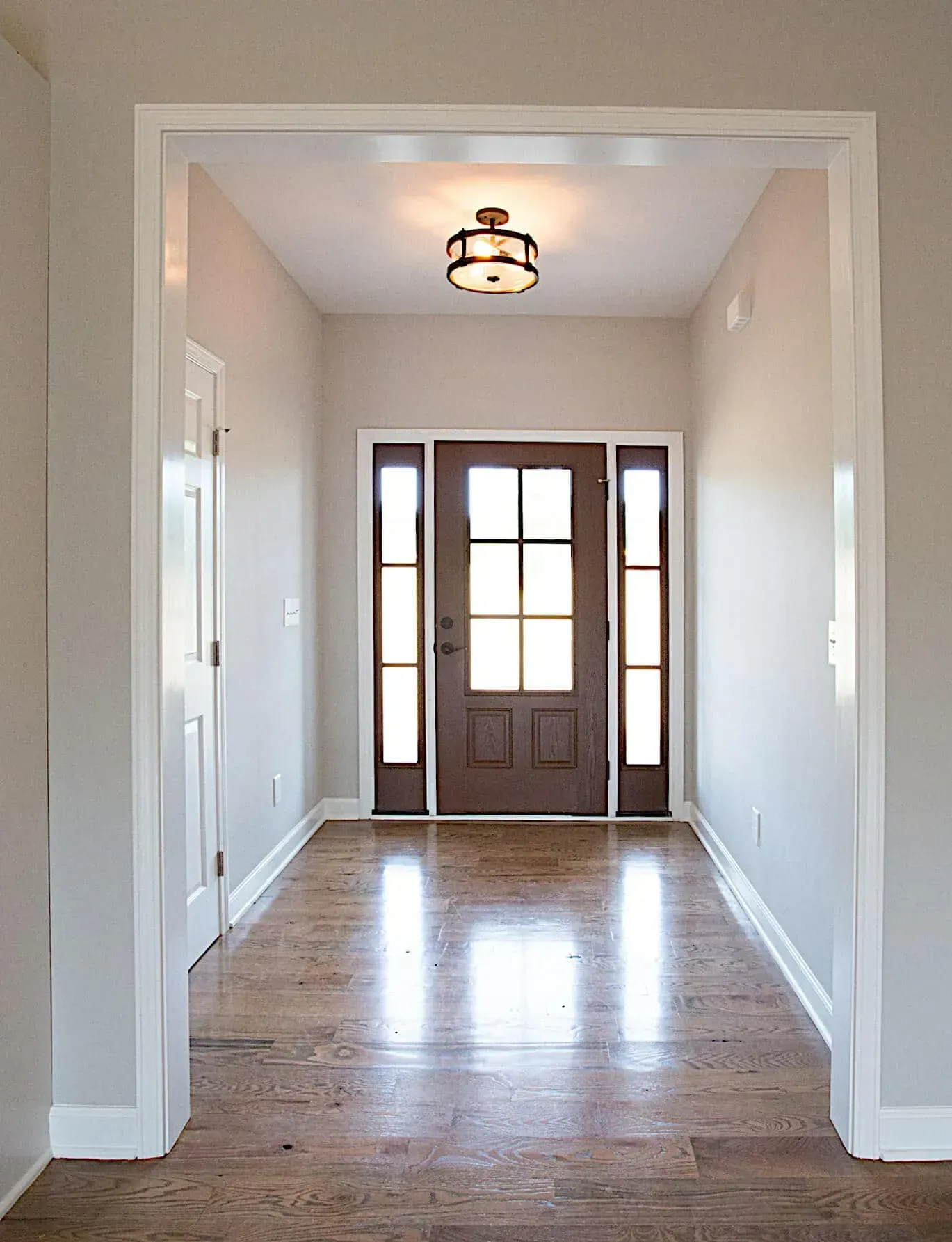A hallway with a wooden door and a light on the ceiling