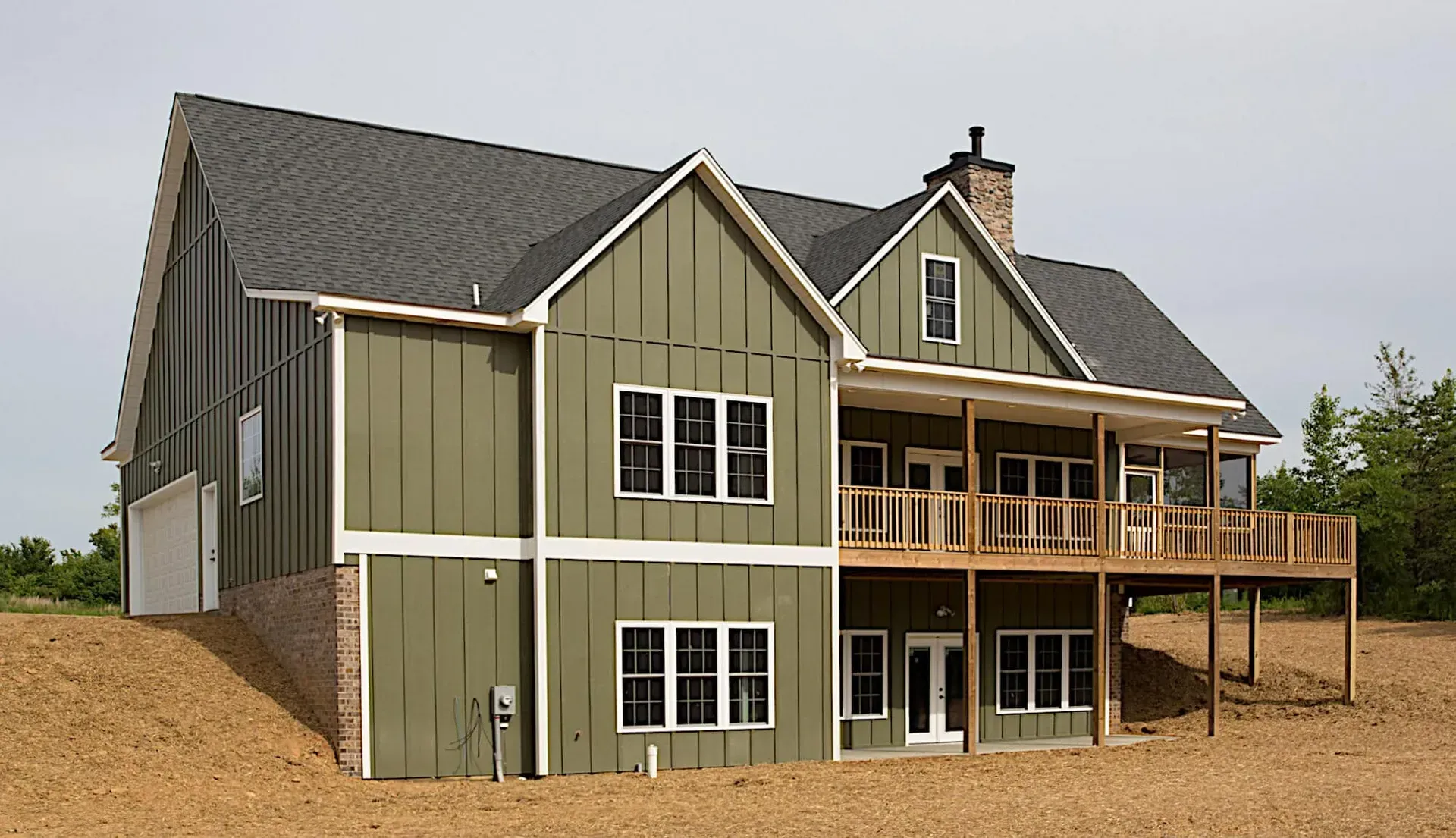 A large house with green siding and a large deck
