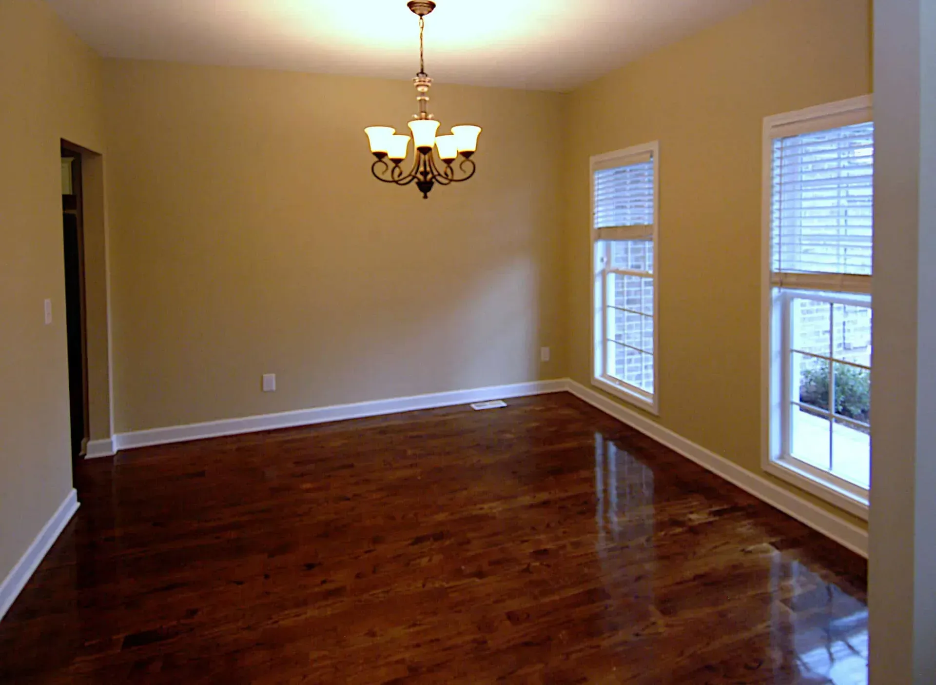 An empty dining room with hardwood floors and a chandelier
