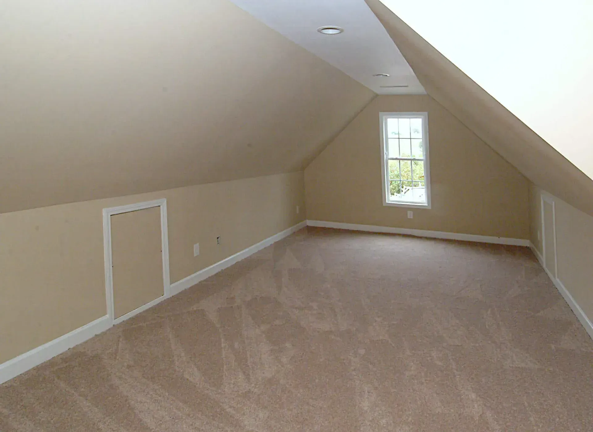 An empty attic with a slanted ceiling and a window